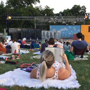 A woman reads a book while lying in front of a stage.