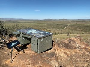 A desk sitting atop a short mountain overlooking an empty landscape.